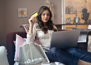 a woman holding a credit card in front of a laptop